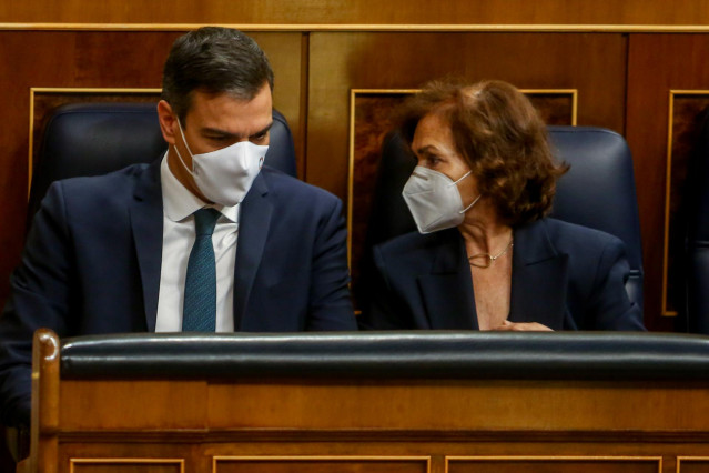 El presidente del Gobierno, Pedro Sánchez, habla con la vicepresidenta primera del Gobierno, Carmen Calvo, durante una sesión plenaria en el Congreso