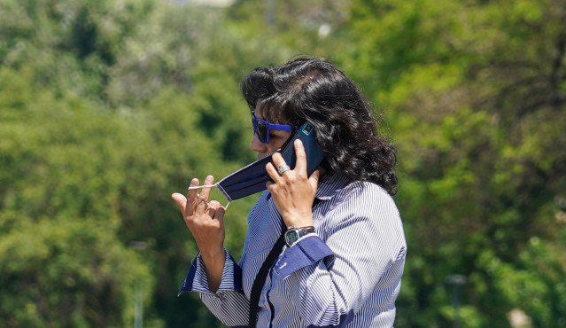 Una mujer se quita la mascarilla para hablar por teléfono en Sevilla a 21 de mayo del 2020