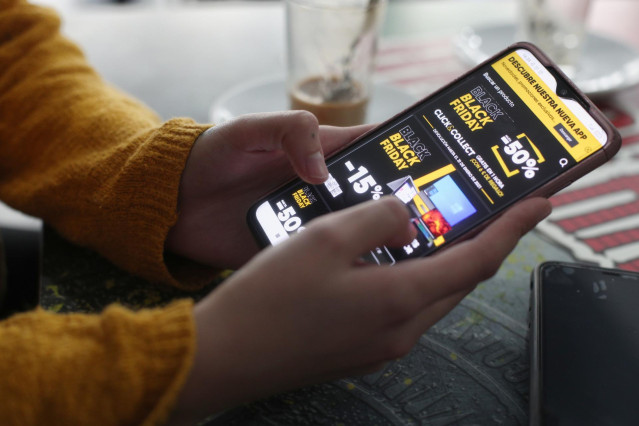 Una joven consulta las ofertas de Black Friday de un comercio en su móvil, en Madrid (España), a 15 de noviembre de 2020.