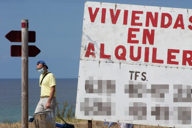 Un hombre camina junto a un cartel de viviendas en alquiler