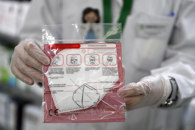 Una farmacéutica muestra una mascarilla de FFP2.