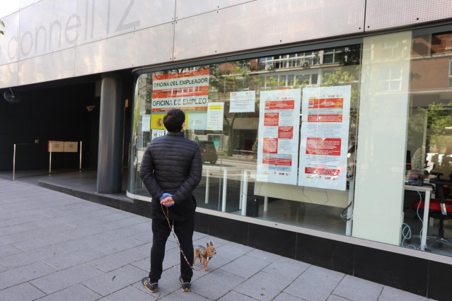 Un hombre pasa con su perro frente a una oficina de Empleo en Madrid