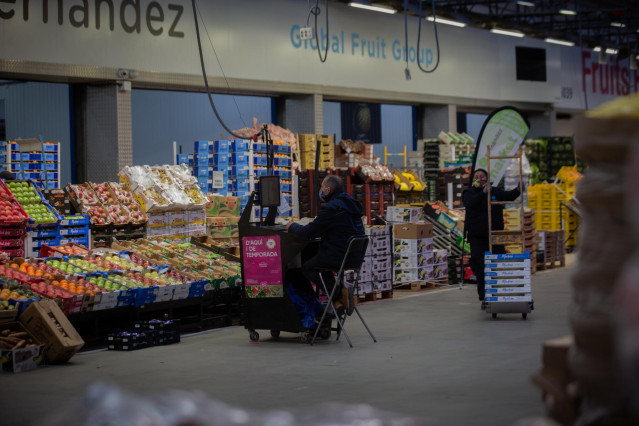 Un hombre trabaja frente a un puesto de frutas en Mercabarna, en Barcelona