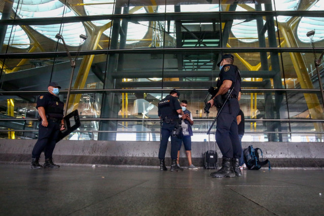Agentes de Policía Nacional piden la documentación en el aeropuerto de Madrid en uno de los controles por la COVID-19