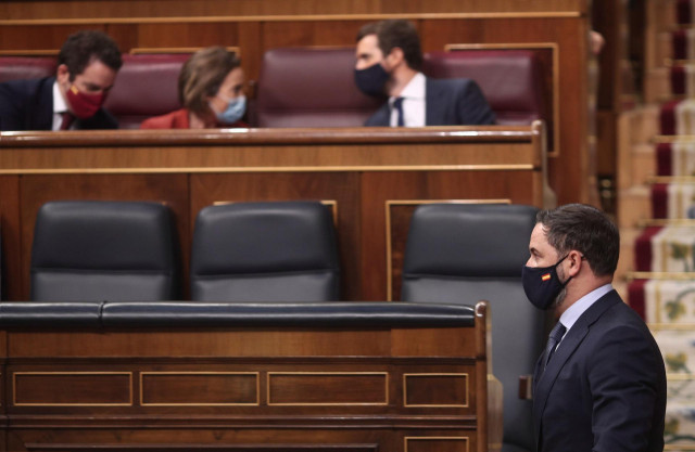 El presidente de Vox, Santiago Abascal, pasa por delante del (I-D) diputado del PP, Teodoro García Egea; la portavoz del PP en el Congreso de los Diputados, Cuca Gamarra; y el presidente del PP, Pablo Casado, durante una sesión plenaria