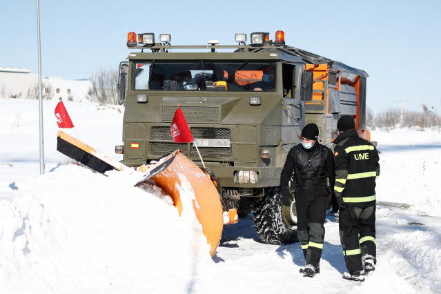 Una excavadora de la Unidad Militar de Emergencias (UME) y dos militares durante la limpieza de una de las carreteras llenas de nieve y hielo tras el paso de la borrasca 'Filomena', en el Polígono El Prado, en Valdemoro, Madrid (España), a 12 de enero de