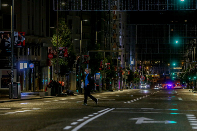 Un hombre cruza la calle durante la primera noche de toque de queda en Madrid (España), a 26 de octubre de 2020. El Gobierno central anunció el pasado domingo la aprobación del estado de alarma para toda España, que entró en vigor ese mismo día, y que imp