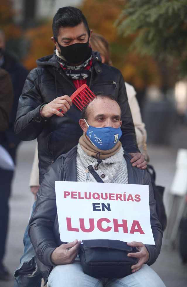 Un peluquero peina a un hombre durante una concentración frente al Congreso de los Diputados