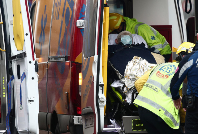 Varios trabajadores sanitarios introducen a un herido en una ambulancia tras la explosión en la calle Toledo de Madrid