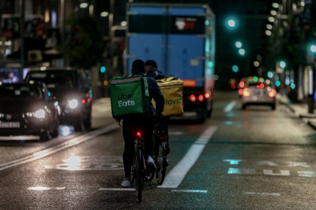 Un rider de Glovo y otro de Uber Eats circulan durante la primera noche de toque de queda en Madrid (España), a 26 de octubre de 2020. El Gobierno central anunció ayer la aprobación del estado de alarma para toda España, que entró en vigor ayer mismo y qu