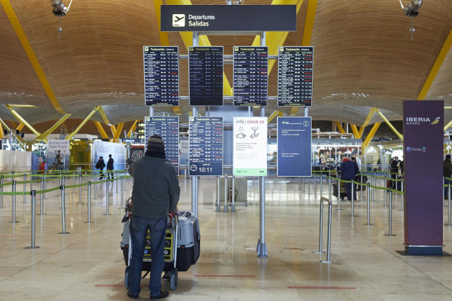 Un pasajero observa los paneles indicativos de la situación de los vuelos donde se pueden observar varios trayectos cancelados en la terminal 4 del aeropuerto Madrid-Barajas