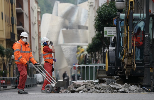 Dos operarios trabajan en la obra de una calle cerca del Museo Guggenheim