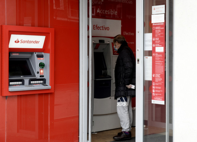 Un hombre saca dinero de un cajero del Banco Santander.