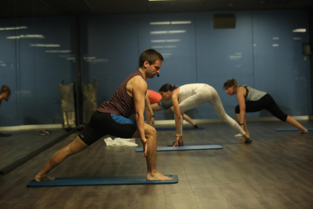 Un entrenador imparte clase a varias personas en una clase de Body Balance en un gimnasio de la cadena O2 en Madrid (España)