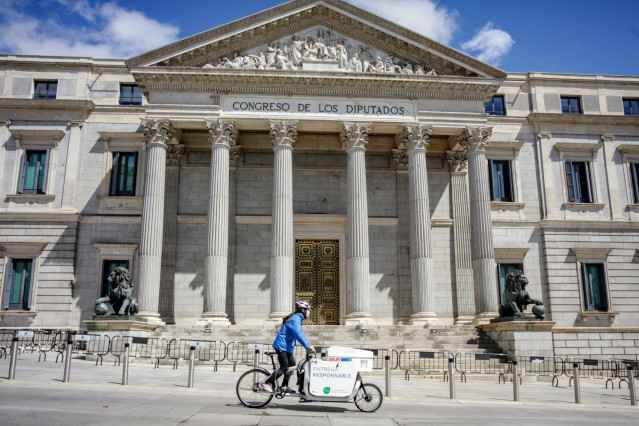 Un repartidor pasa por delante del Congreso de los Diputados