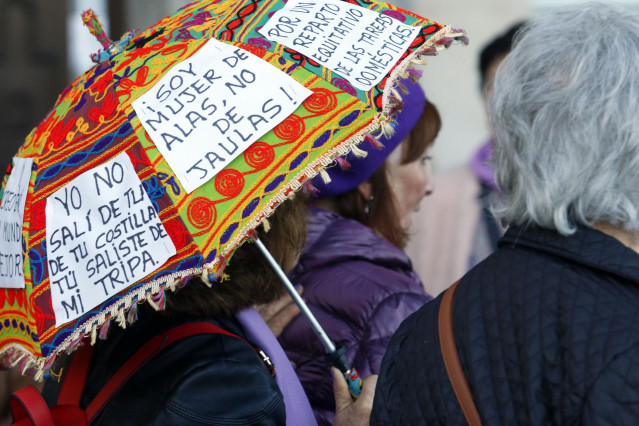 Archivo - Una mujer pega carteles reivindicativos en su paraguas durante la marcha por el Día Internacional de la Mujer en Málaga, (Andalucía, España), a 08 de marzo de 2020. (Foto de archivo).