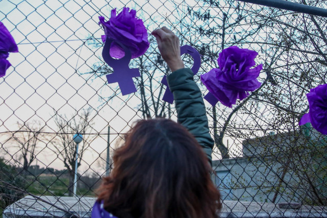 Una mujer cuelga símbolos feministas en una valla durante una marcha y batukada feminista en el CIE de Aluche, en Madrid (España), a 5 de marzo de 2021.