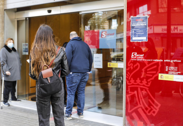 Archivo - Varias personas con cita previa esperan para entrar en una oficina del SEPE