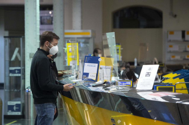 Un cliente es atendiendo en la Oficina de Correos de Cibeles, en Madrid, (España).