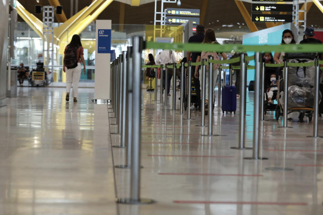 Archivo - Pasajeros cerca de páneles informativos en la terminal T4 del aeropuerto Adolfo Suárez Madrid-Barajas, en Madrid