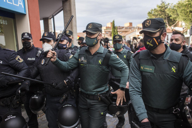 Un grupo de agentes vigila y se protege durante un mitin de Vox, a 21 de abril de 2021, en Navalcarnero, Madrid (España).