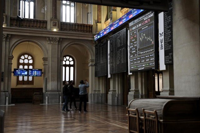 Un grupo de personas realiza una fotografía a los valores del Ibex 35 en el Palacio de la Bolsa, a 19 de abril de 2021, en Madrid, (España).