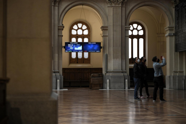 Un grupo de personas realiza una fotografía a los valores del Ibex 35 en el Palacio de la Bolsa