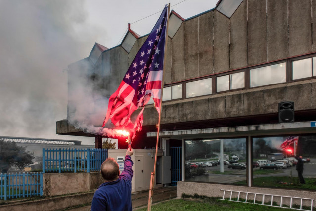 Archivo - Un trabajador de Alcoa San Cibrao quema una bandera de Estados Unidos delante de la factoría tras conocer la anulación del TSXG del ERE de la empresa en Cervo, A Mariña, Lugo
