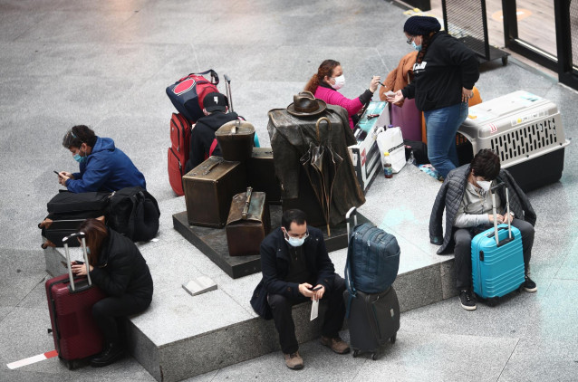 Archivo - Viajeros esperan en un asiento de la estación de tren de Atocha