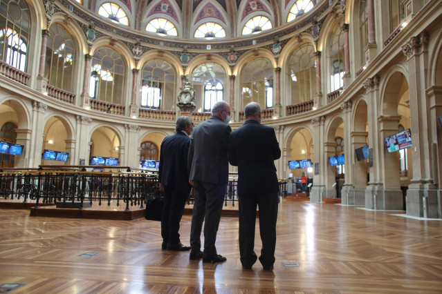 Tres hombres observan valores económicos en el Palacio de la Bolsa, a 13 de mayo de 2021, en Madrid (España). El Ibex 35 cedía un 1,94% en la media sesión de este jueves, alejándose de los 8.900 puntos, arrastrado por las caídas registradas ayer en Wall S