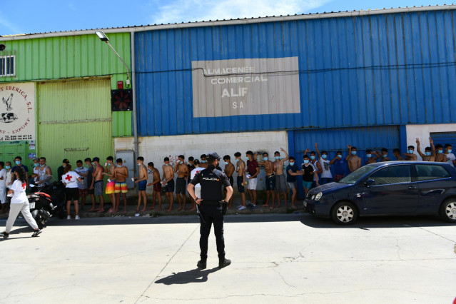 Un grupo de jóvenes migrantes marroquíes en fila en las inmediaciones de una nave tras llegar a nado a Ceuta en las últimas horas