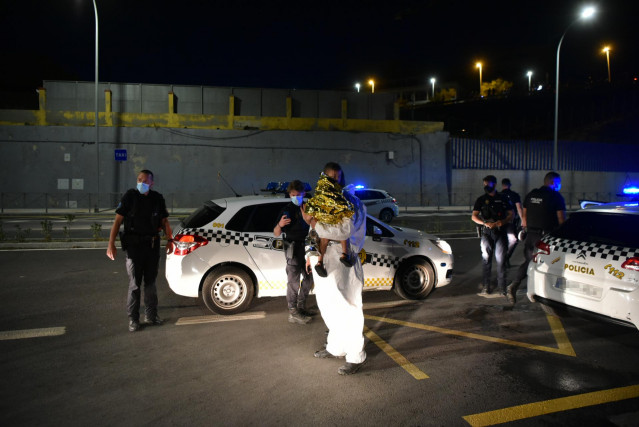 Un hombre migrante junto a policías en Ceuta tras acceder de forma irregular a la ciudad española