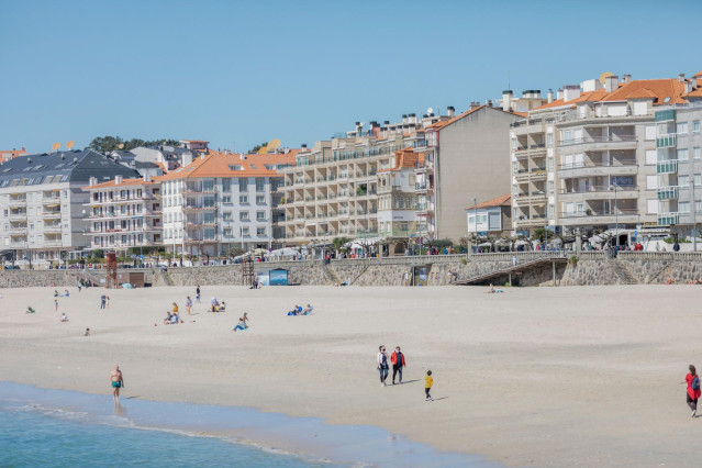 Archivo - Varias personas pasean por la playa de Sanxenxo.
