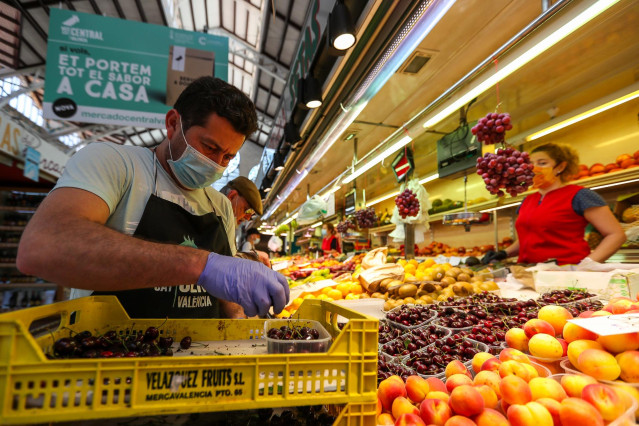 Archivo - Un hombre trabaja colocando la fruta en una una frutería del Mercado Central de Valencia