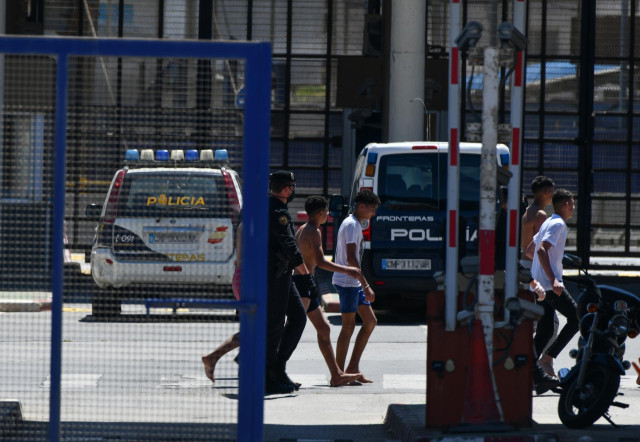 Un grupo de jóvenes migrantes marroquíes en las inmediaciones de la valla de Ceuta con varios agentes de la Policía Nacional