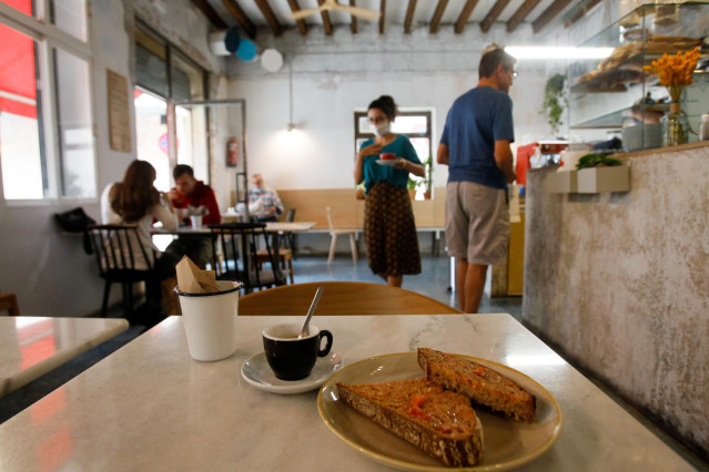 Archivo - Tostadas y café en una mesa del interior de un bar.