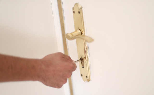 Archivo - Un hombre introduce una llave en la cerradura de la puerta de su vivienda