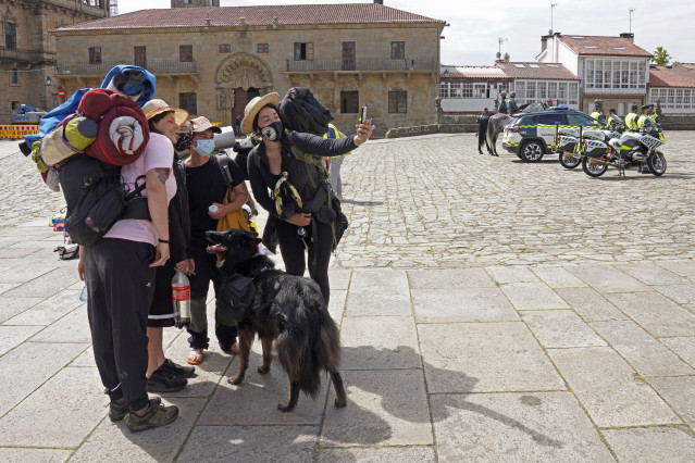 Varios peregrinos se toman una foto, a su llegada a la Catedral de Santiago