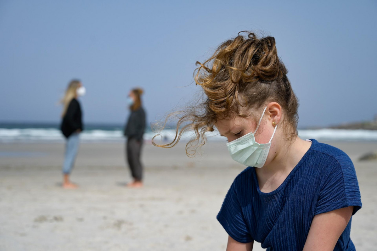 Archivo - Una niña con mascarilla en la playa.