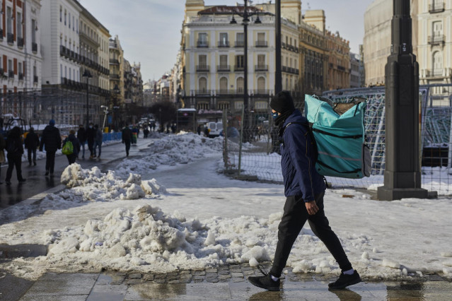 Archivo - Un empleado de Deliveroo camina con su mochila de reparto por la Puerta del Sol nevada tras restablecer parcialmente el servicio, en Madrid, (España), a 15 de enero de 2021. El paso de la borrasca 'Filomena' provocó una gran nevada por lo que la