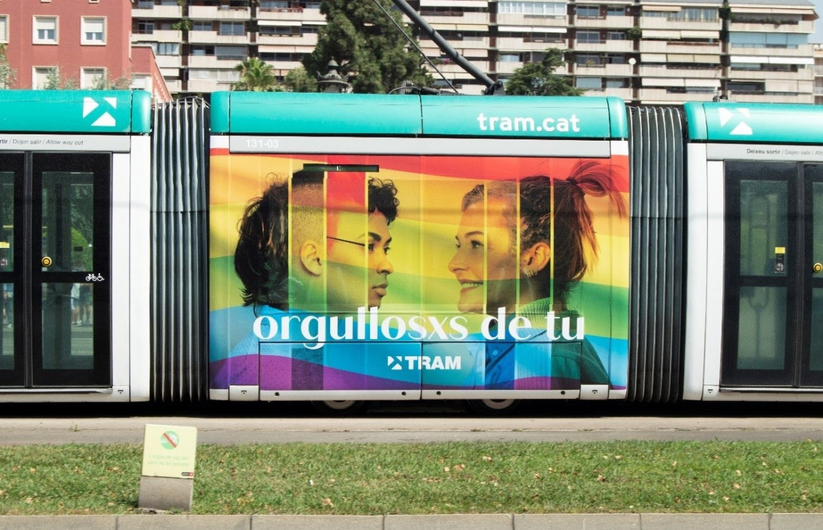 Un tramvia amb la imatge de la bandera LGTBI amb el lema 'orgullosxs de tu'.
