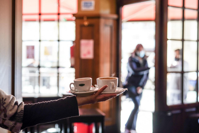 Archivo - Un camarero sirve varios cafés en una cafetería de Vitoria