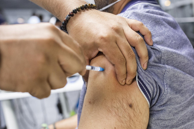 Un sanitario administra una dosis de la vacuna de Pfizer a un hombre en el Wizink Center