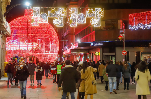 Archivo - Transeúntes pasean bajo las luces navideñas, en Vigo, en diciembre de 2020.