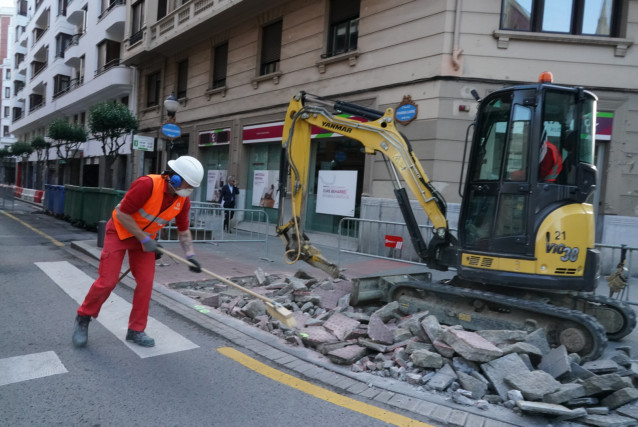 Archivo - Un operario trabaja junto a una máquina en la obra de una calle
