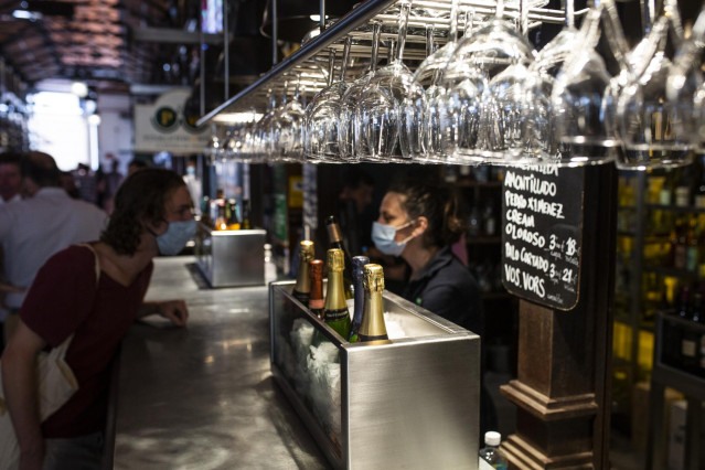 Archivo - Una persona conversa con una camarera durante la reapertura del Mercado de San Miguel, a 2 de julio de 2021, en Madrid, (España).