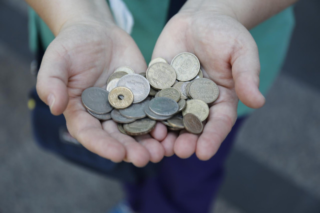 Archivo - Una persona muestra un puñado de monedas de las antiguas pesetas mientras hace cola para entrar en el Banco de España en el último día en el que se pudo cambiar pesetas por euros, a 30 de junio de 2021, en Madrid