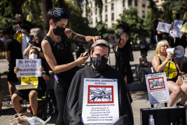 Archivo - Una peluquera corta el pelo a un hombre durante una protesta frente al Congreso de los Diputados para exigir el IVA reducido,  a 30 de junio de 2021, en Madrid, (España).