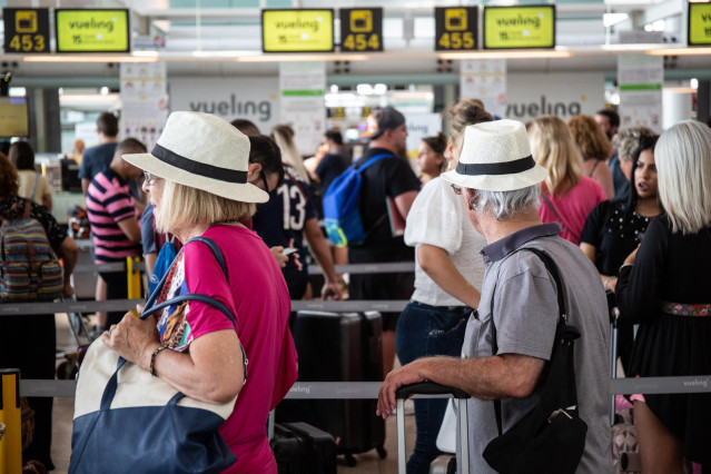 Archivo - Diferentes viajeros esperan en el puesto de Check-In de la compañía Vueling en el Aeropuerto 'Josep Tarradellas Barcelona-El Prat',