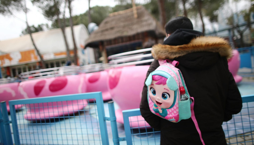 Archivo - Un hombre con una mochila infantil en el Parque de Atracciones.